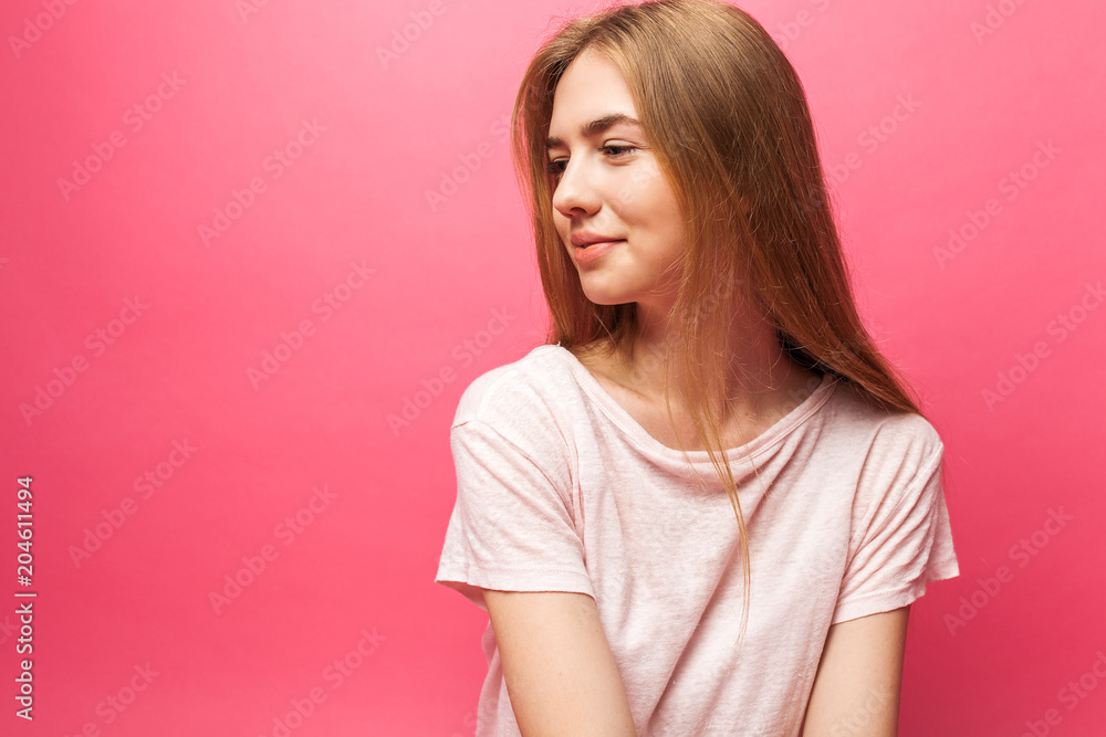 Portrait of a beautiful young girl standing on a pink background, looking away, smiling and rejoicing Portrait of a beautiful young girl standing on a pink background, looking away, smiling and rejoicing