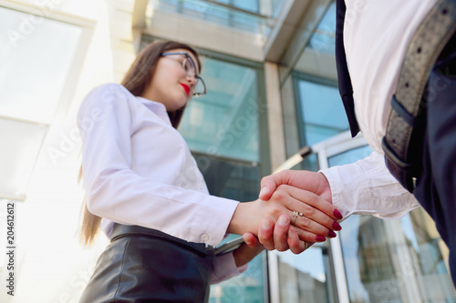 Handshake of a man and a woman against a multi-storey office building. Make a deal. Friendly relations. Office staff