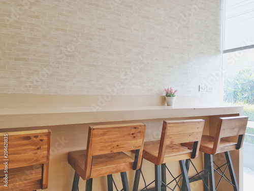 Cafe wall table and flowerpot on top of table and wood chair with natural light pass through white curtain and pattern wall background