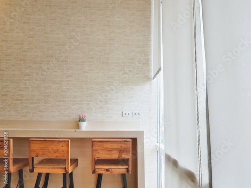 Cafe wall table and flowerpot on top of table and wood chair with natural light pass through white curtain and pattern wall background