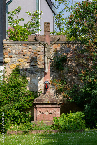 Big crucific in a garden in front of a old stony wall  photo