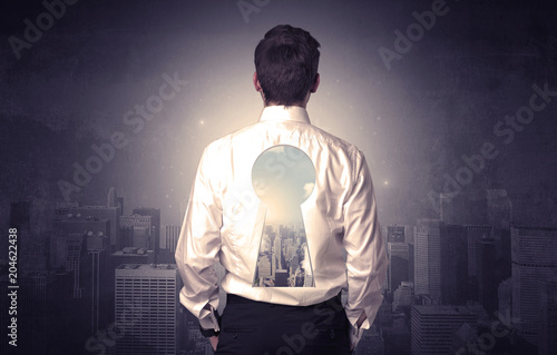 Young businessman standing and thinking with keyhole on his back and city graphic around