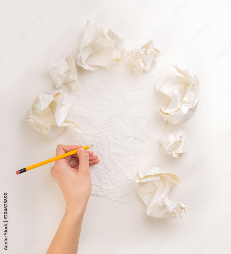 Female hand trying to write next to a few crumpled paper balls Female hand trying to write next to a few crumpled paper balls