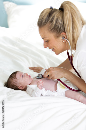 Pediatrician examines baby with stethoscope at home