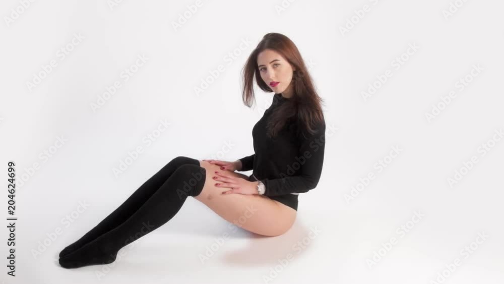 woman dancer with long straight hair in studio wears black high-knee socks sits on white background in studio woman dancer with long straight hair in studio wears black high-knee socks sits on white background in studio