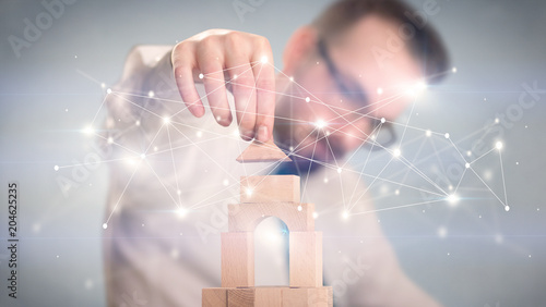 Young handsome businessman using wooden building blocks with interconnected lines and dots around him