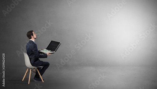 Quadro em tela Businessman staying in an empty grey dark room with stuffs on his lap