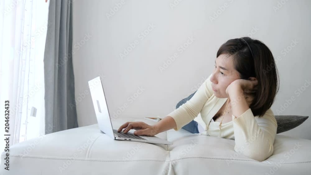 Asian woman lying on bed and using laptop at home, slow motion. Asian woman lying on bed and using laptop at home, slow motion.