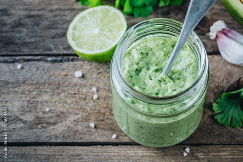 Photo green salad dressing with avocado, lime and cilantro in a glass jar