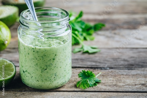 Fototapeta green salad dressing with avocado, lime and cilantro in a glass jar