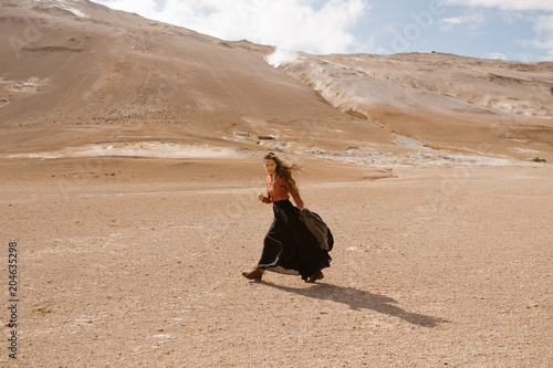Woman wearing a long dress walking in a windy desert