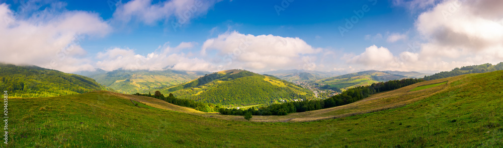panorama of beautiful countryside in autumn. beautiful landscape with forested mountains in a distance and grassy rural field under the blue sky with some clouds