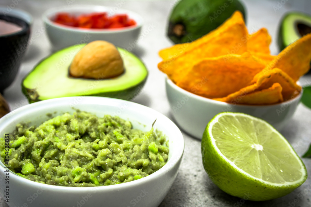 Traditional mexican food - guacamole with avocado and tortilla chips on table, party food for sharing