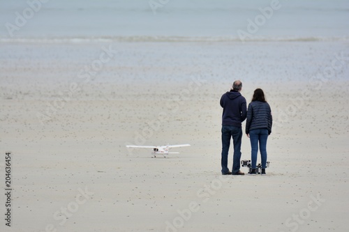 Un couple qui fait voler un avion en modèle réduit sur une plage de Bretagne photo