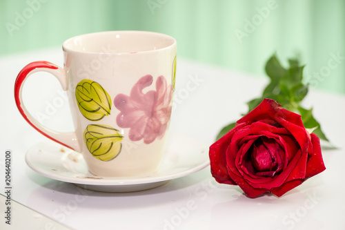 red rose with a cup of tea on the white table
