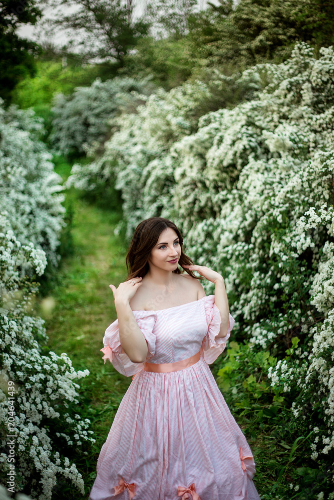 portrait of a beautiful girl in a smart dress on a background of flowering bushes