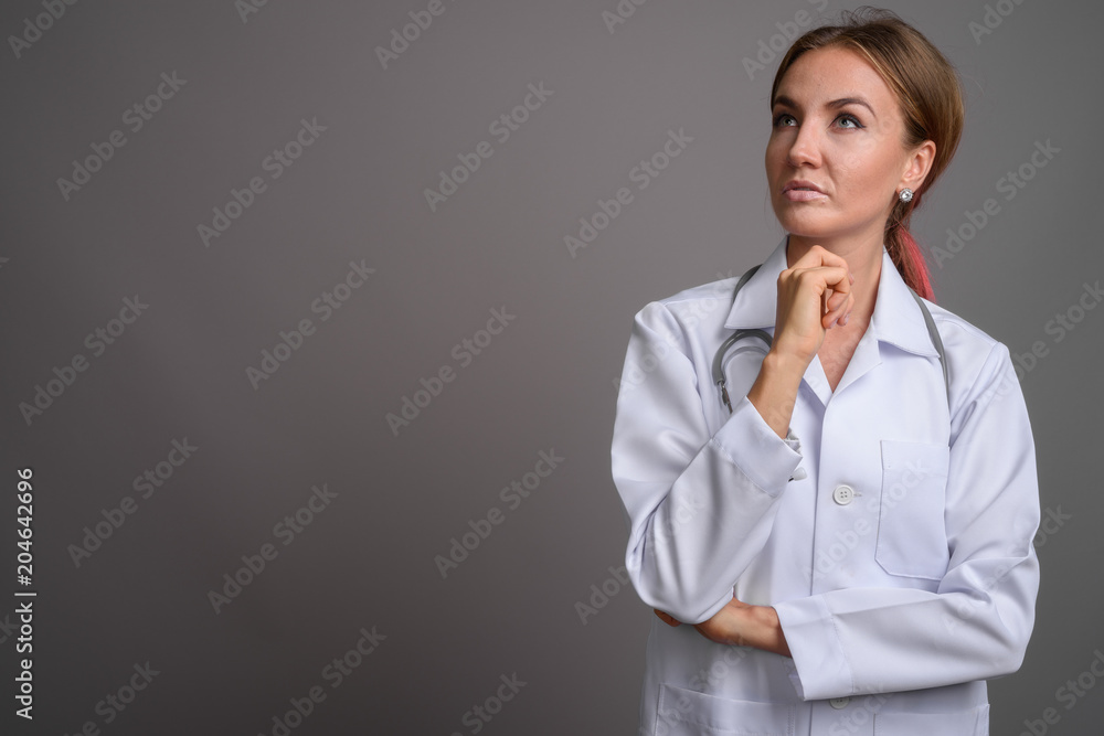 Young beautiful woman doctor against gray background Young beautiful woman doctor against gray background