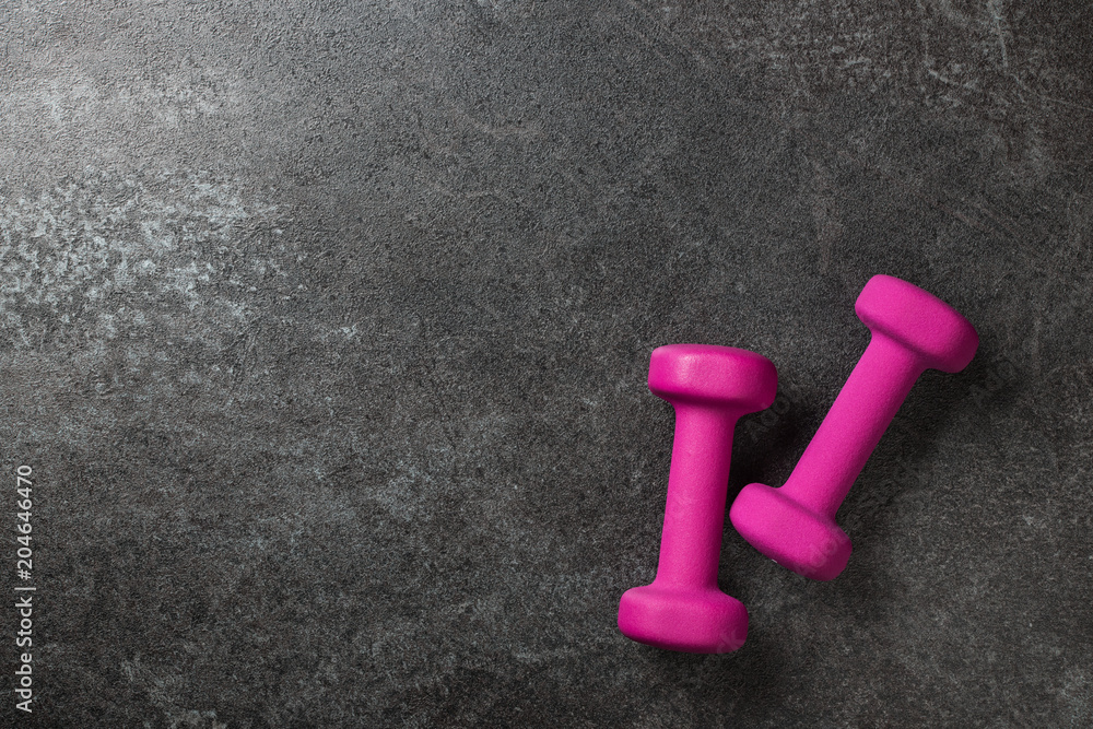 Fitness concept with pink dumbbells on black background Fitness concept with pink dumbbells on black background