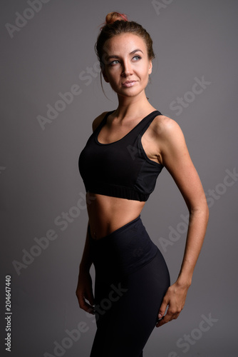 Young beautiful woman ready for gym against gray background © Ranta Images