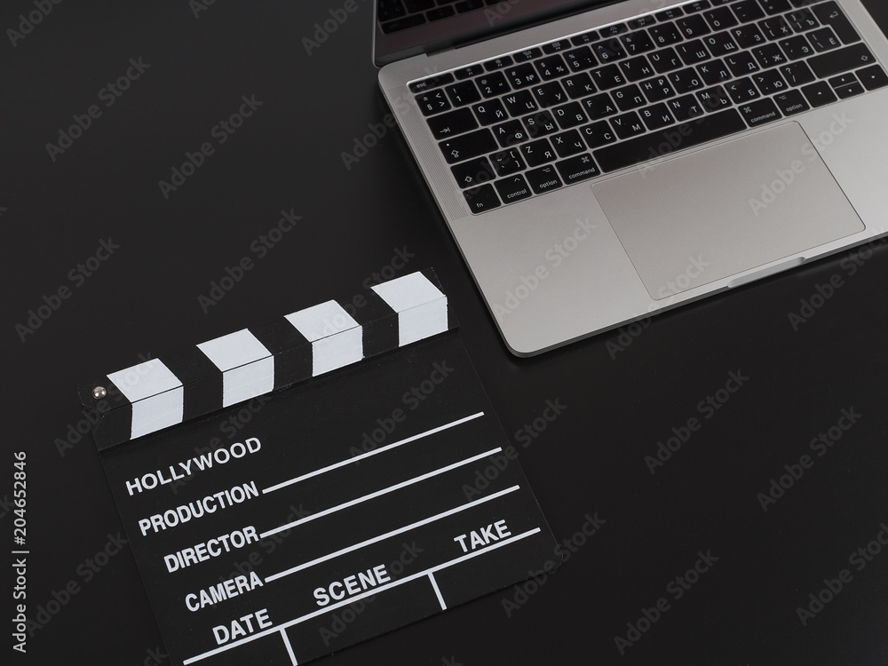 Camera with laptop and clapper movie isolated on black background