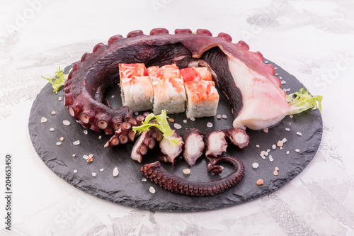 Beautiful octopus tentacle on the dark plate with rolls