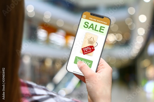 Sale and discount idea, girl with frameless phone on blurred mall background