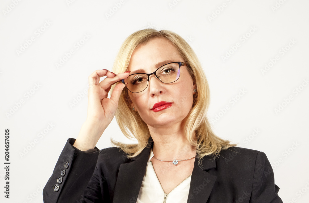 Blonde business woman in glasses and a black jacquer keeps her glasses hand looking at the camera Blonde business woman in glasses and a black jacquer keeps her glasses hand looking at the camera