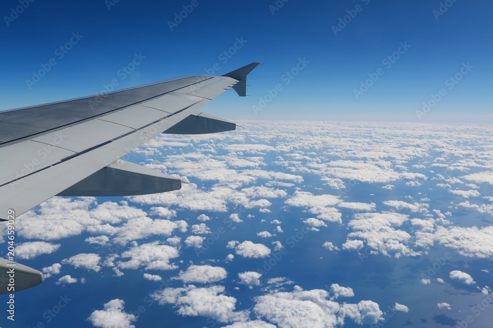 Looking Out Over the Wing of a Commercial Airline Jet to the Atlantic Seaboard over a Blanket of Scattered White Clouds Looking Out Over the Wing of a Commercial Airline Jet to the Atlantic Seaboard over a Blanket of Scattered White Clouds