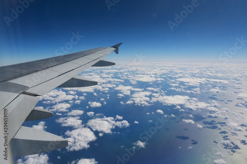 Looking Out Over the Wing of a Commercial Airline Jet to the Atlantic Seaboard over a Blanket of Scattered White Clouds