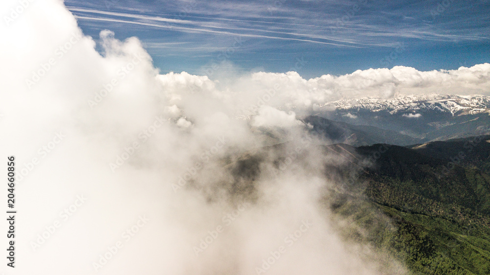 spring landscape with the mountain peaks covered with snow and clouds. aerial view by drone