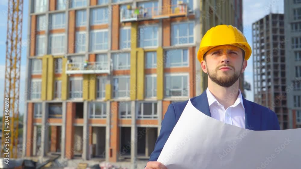 a young male orchid examines a project under construction against the background of buildings. Close-up portrait of a man. a man holds the cherries and project forms in his hands 4k a young male orchid examines a project under construction against the background of buildings. Close-up portrait of a man. a man holds the cherries and project forms in his hands 4k
