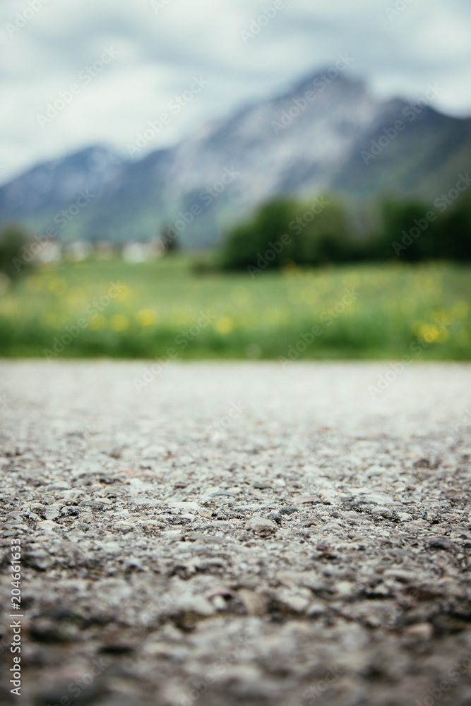 Nahaufnahme Asphalt, unscharfe Berge im Hintergrund Nahaufnahme Asphalt, unscharfe Berge im Hintergrund