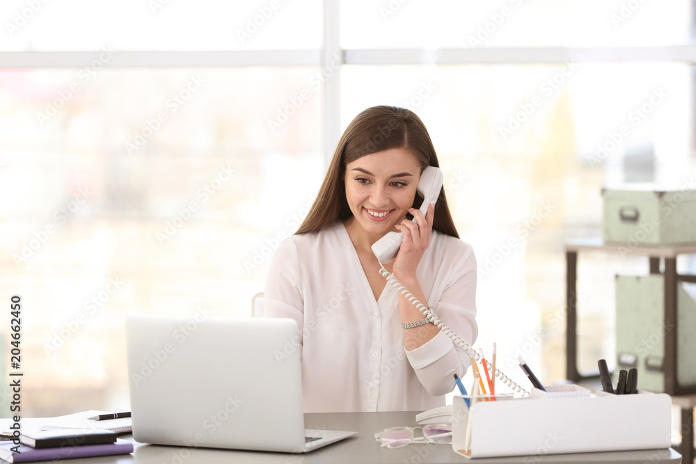 Young woman talking on phone at workplace Young woman talking on phone at workplace