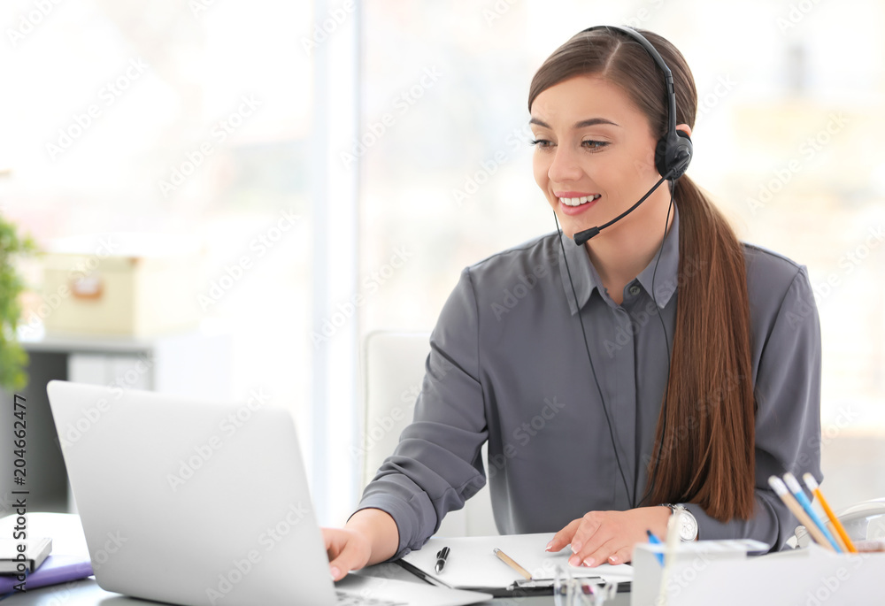 Young woman talking on phone through headset at workplace Young woman talking on phone through headset at workplace