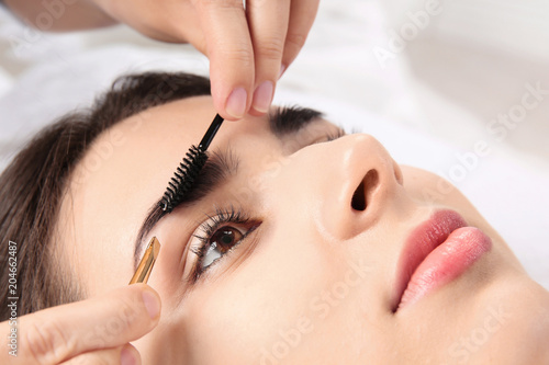 Young woman having professional eyebrow correction procedure in beauty salon, closeup