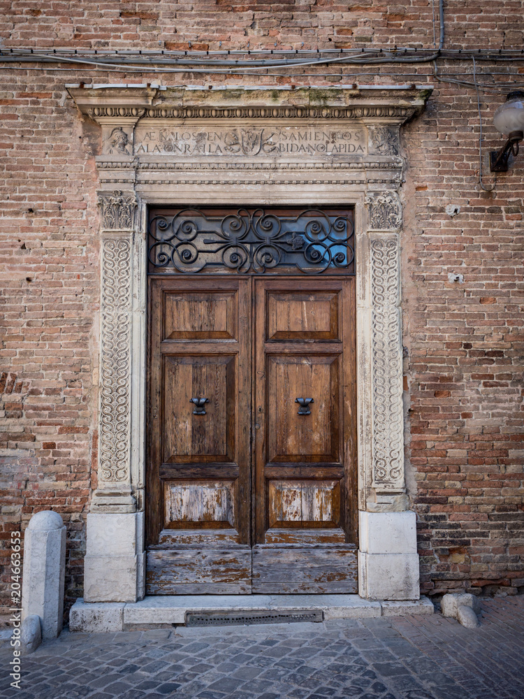 Old wooden portal with columns and architrave in white stone. Old wooden portal with columns and architrave in white stone.