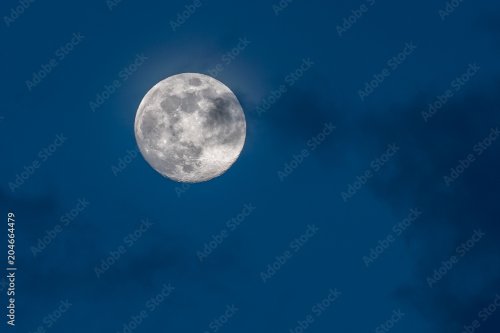 gorgeous full moon in a dark blue night sky gets covered by soft wispy dark clouds gorgeous full moon in a dark blue night sky gets covered by soft wispy dark clouds