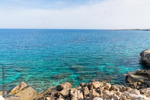 Seacoasr with large boulders and transparent blue water in Cape Greco national park