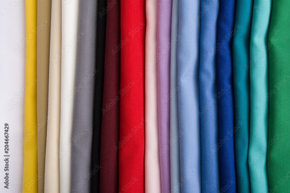A pile of multicolored fabrics. Rainbow fabric background. Pile of bright folded fabric.