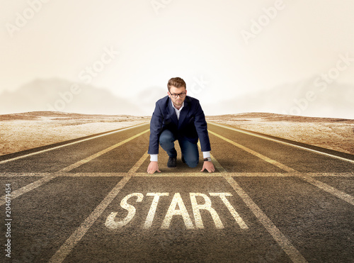 Young determined businessman kneeling before start line