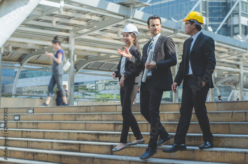 Fotografia engineer team walking with business man at outdoor construction site in city with talking and discussion about planning project progress to successful construction business property estate investment