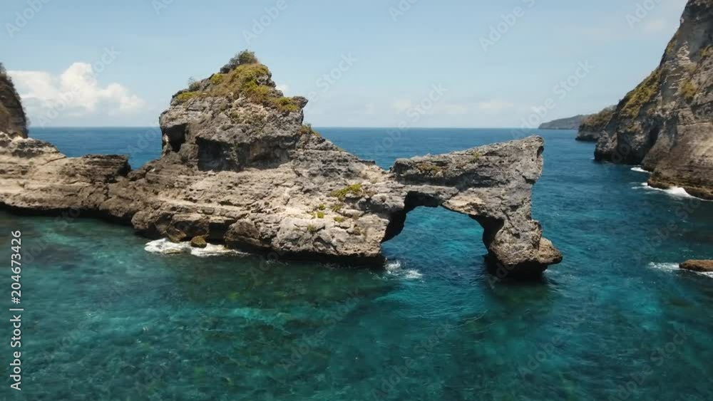 Rock in the ocean at Atuh beach on Nusa Penida island, Indonesia. Aerial view of Rocks in a blue sea lagoon with breaking waves. 4K video. Travel concept. Aerial footage. Rock in the ocean at Atuh beach on Nusa Penida island, Indonesia. Aerial view of Rocks in a blue sea lagoon with breaking waves. 4K video. Travel concept. Aerial footage.