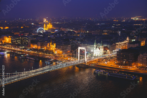 Beautuful super-wide angle aerial night view of Budapest, Hungary, with Danube river, Parliament building and scenery beyond the city, seen from observation point of Gellert Hill
