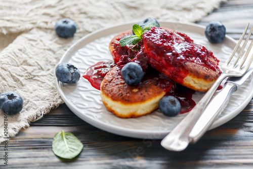 Curd pancakes with berry sauce on a plate.