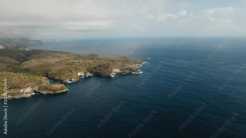 Aerial view of Rocky coast with high cliffs, sea surf with breaking waves on the coast, Nusa Penida, Bali, Indonesia. Ocean with waves and rocky cliff. 4K video. Travel concept Aerial footage Aerial view of Rocky coast with high cliffs, sea surf with breaking waves on the coast, Nusa Penida, Bali, Indonesia. Ocean with waves and rocky cliff. 4K video. Travel concept Aerial footage