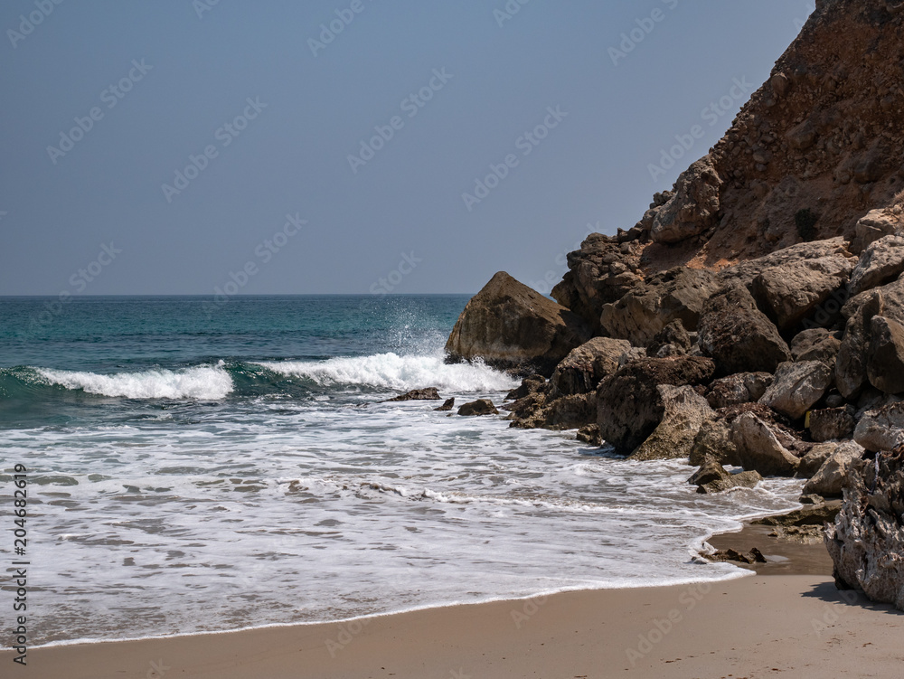 Closer shot of a deserted beach with an outcropping of rocks in the distance Closer shot of a deserted beach with an outcropping of rocks in the distance