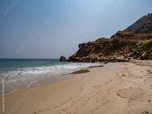 Deserted beach with an outcropping of rocks in the distance