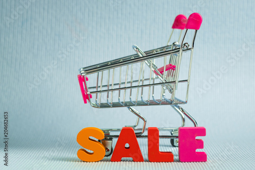 Sale colorful wooden text and shopping cart or supermarket trolley on blue background with copy space, shopping discount and merketing concept. template for add text or photo. photo