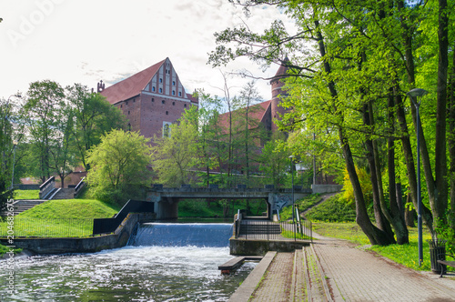 Waterfall at Lyna River with castle in background in Olsztyn, poland.