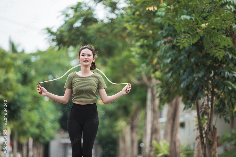 fit young woman with jump rope in a park